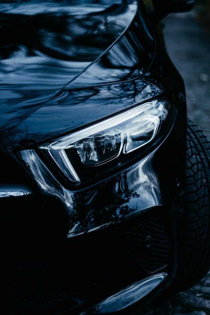 Close-up of a modern cars sleek headlight at night, showcasing automotive elegance in Berlin.