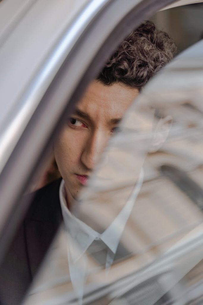 Young man in a suit looking thoughtfully through a car window.