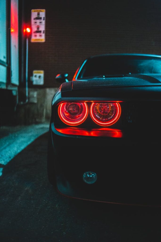 Close-up of a luxury sports car with glowing taillights parked in a city alley.
